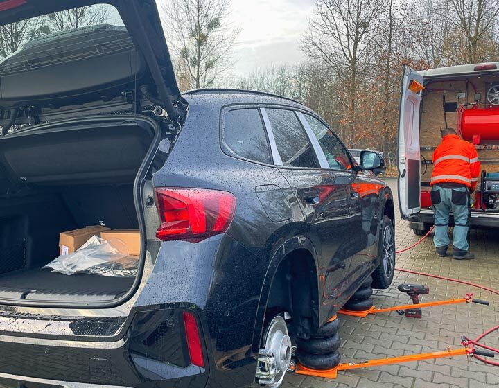 Mobilna wulkanizacja wymienia opony na zimowe w samochodzie SUV marki BMW X1 na parkingu