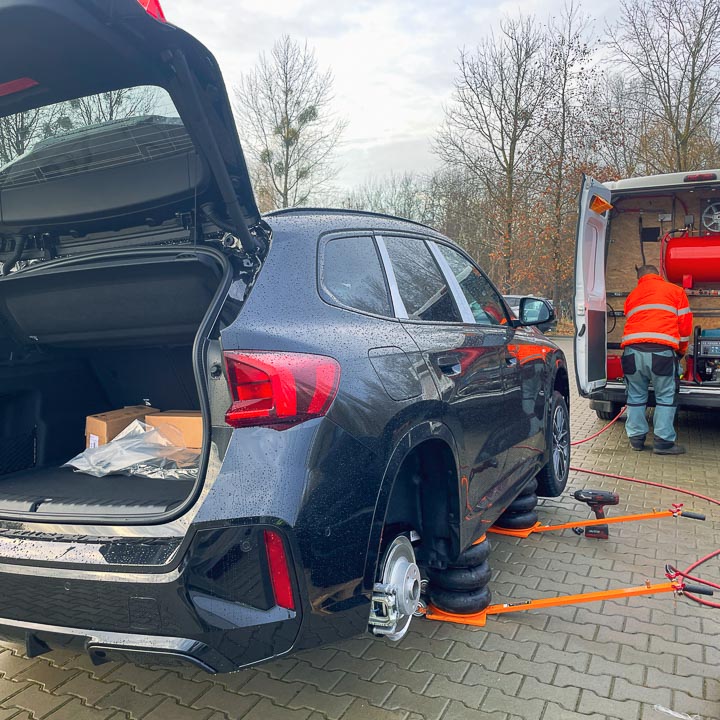 Mobilna wulkanizacja wymienia opony na zimowe w samochodzie SUV marki BMW X1 na parkingu